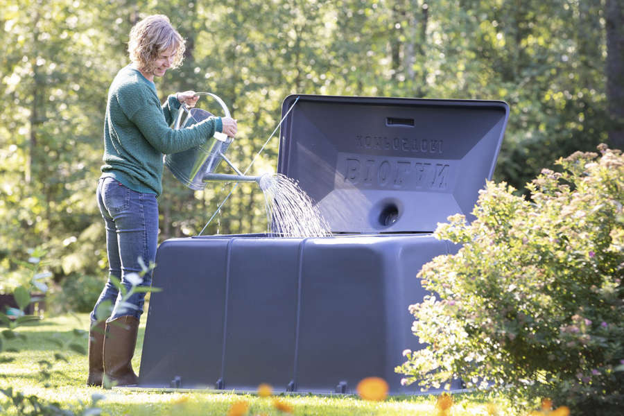 Nainen kastelee puutarhakompostia